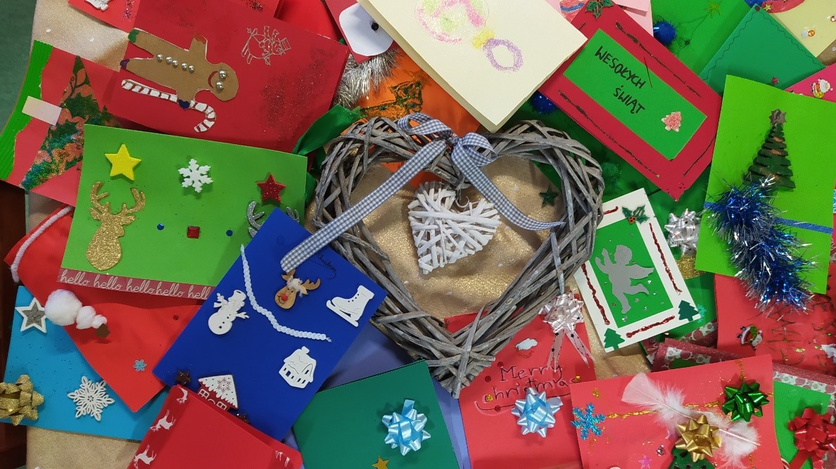 Na zdjęciu kolorowe kartki bożonarodzeniowe, ręcznie wykonane, na środku ozdoba - wiklinowe serce