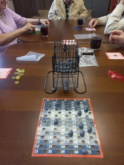 Zdjęcie. Na głównym planie mamy grę Bingo leżąca na brązowym stole.