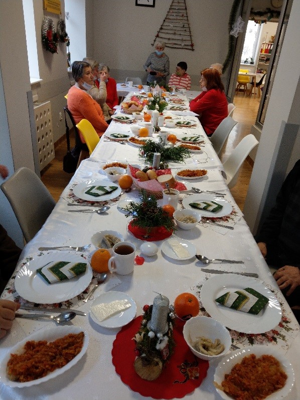  na zdjęciu widać świątecznie udekorowany wigilijny stół obok stolik z ciastami oraz cukierkami.