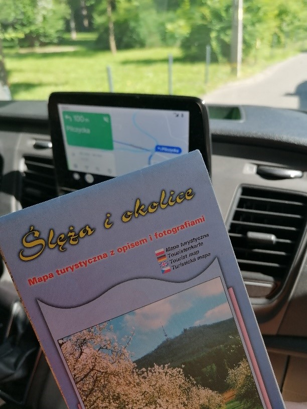  W tle samochodu służbowego jest ustawiona aplikacja w ekranie głównym mapa google z miejscem dojazdu oraz mapa turystyczna z opisem i fotografiami