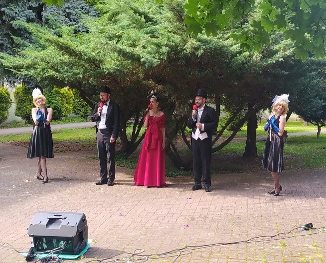 Na zdjęciu grupa pięciu artystów śpiewających w ogrodzie DPS
