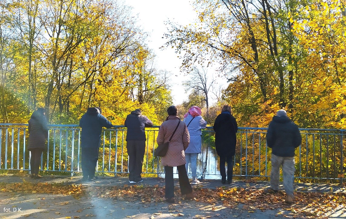 Na zdjęciu siedem osób patrzących na jesienny pejzaż nad rzeką