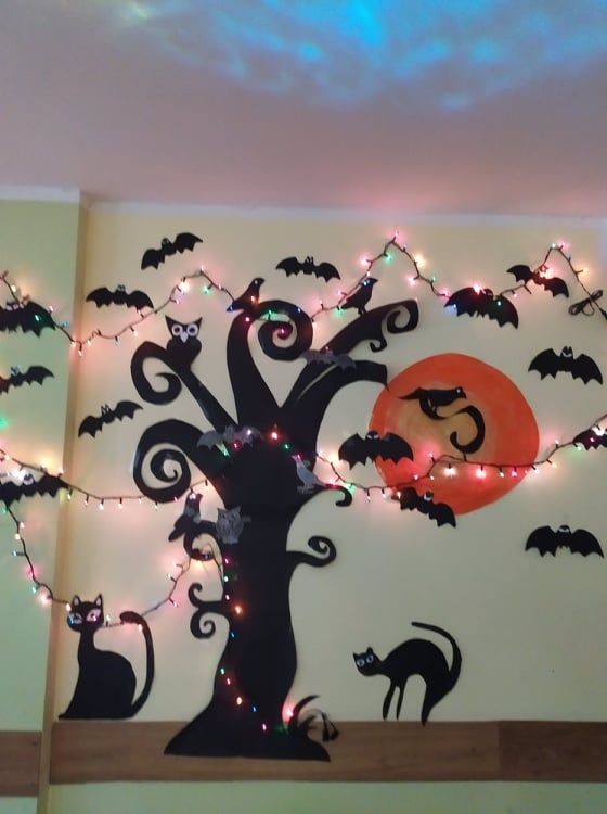 dekoracja ścienna na zabawę andrzejkową - czarny kontur drzewa, obok drzewa dwa czarne koty, powyżej latające nietoperze, w głębi pełnia księżyca.