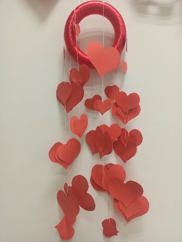 Fotografia  przedstawia ozdobę walentynkową – czerwone serca zawieszone na czerwonej obręczy