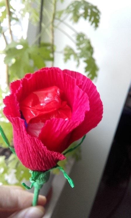 Fotografia Przedstawia czerwony kwiat wykonany z bibuły