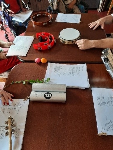 Zdjęcie nr.14 Przedstawia śpiewniki oraz instrumenty muzyczne, które leżą na brązowym stole.