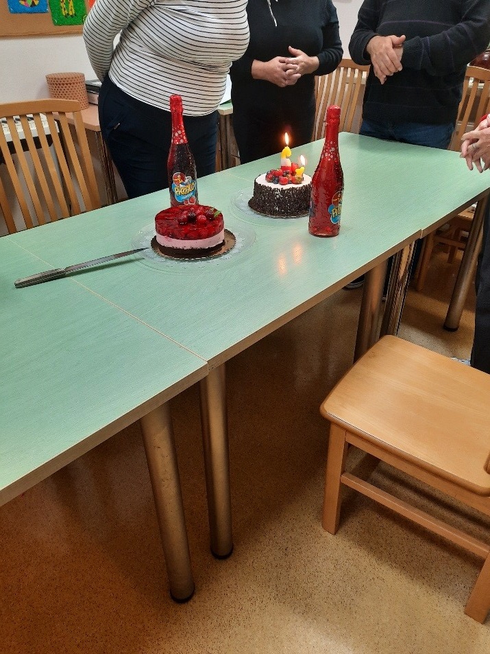 na zdjęciu na stole widać tort ze świeczkami, ciasto z galaretką i szampana bezalkoholowego