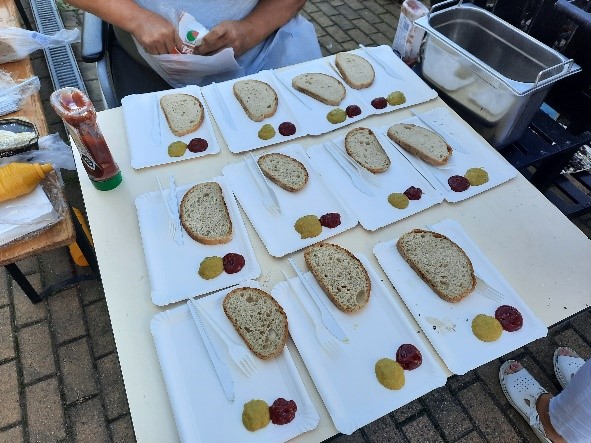 Zdjęcie przedstawia stolik a na nim tacki z chlebem, ketchupem i musztardą